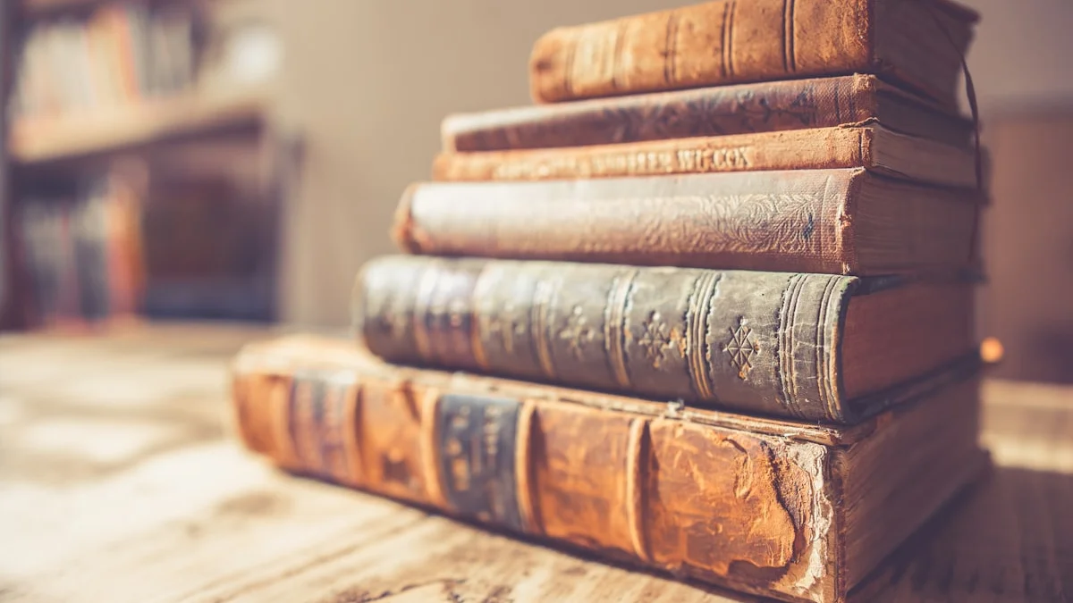 A stack of worn antique hardbound books in warm amber light on a wooden table. — a The Obsidian Key guide to Daily Ritual Review: Does the Key Protocol Hold Up.