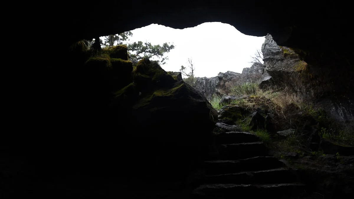 Stone steps climb out of a dark cave toward overcast daylight and mossy rock. — a The Obsidian Key guide to Is Your Practice Real: 9 Discernment Questions.