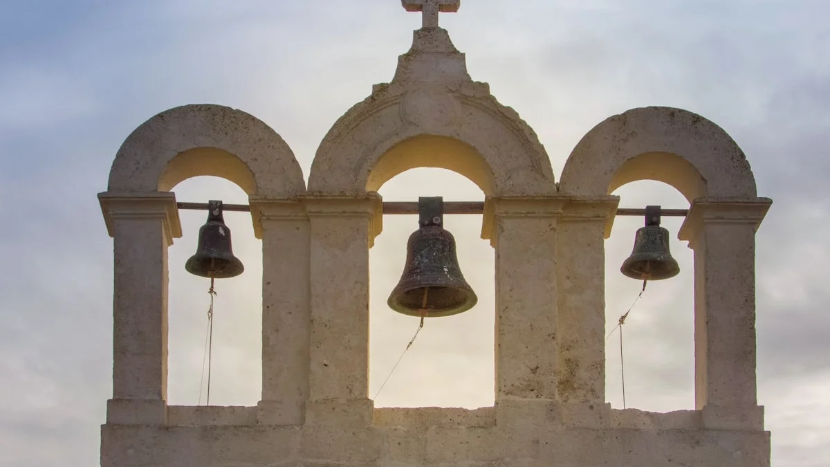 Three bronze bells hanging in the stone arches of an old bell gable. — a The Obsidian Key guide to Seven Emotional Mistakes That Distort the Signal.
