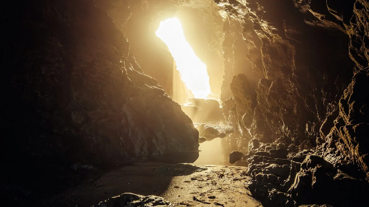 Golden light pours through a sea cave opening onto wet sand and still water. — a The Obsidian Key guide to Get the Obsidian Key: The Emotional Signal Path.