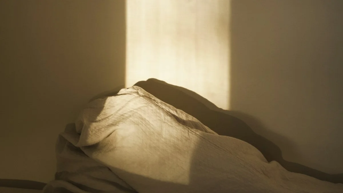 Warm dawn window light falls across rumpled linen bedding. — a The Obsidian Key guide to Morning Light and the First Hour of the Day.