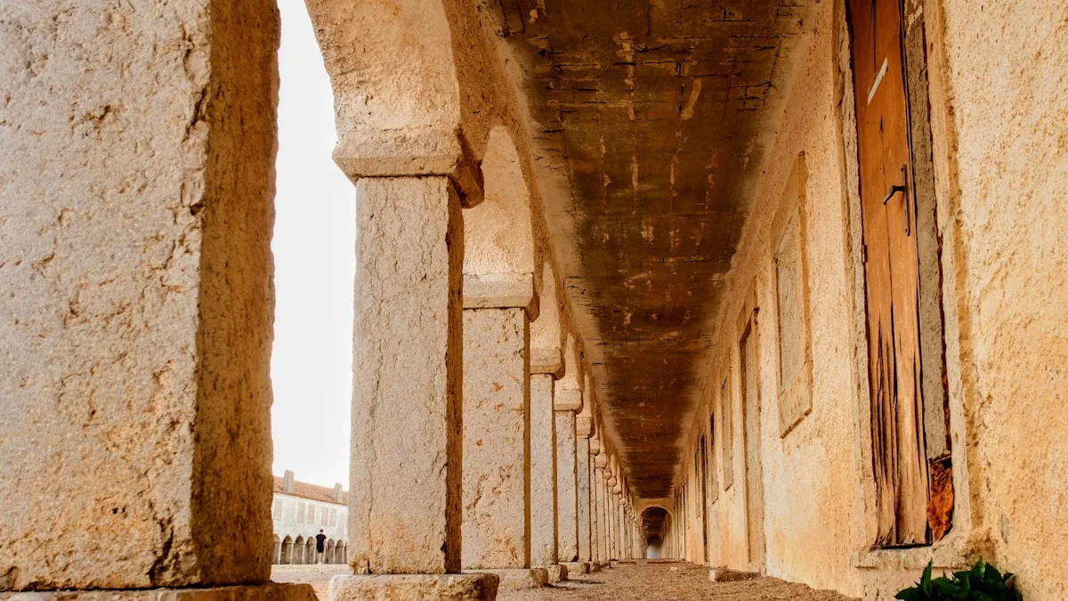 A long empty stone arcade receding into darkness beside old wooden doors. — a The Obsidian Key guide to A Night That Passed Like a Hallway: Reading Bad Sleep.