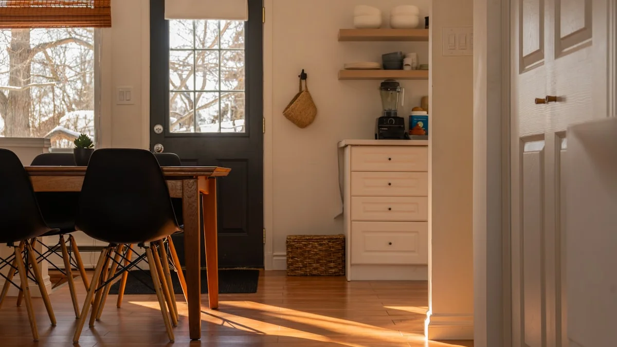 Warm sunlight crosses the wooden floor of a kitchen and dining room with a dark door and empty chairs. — a The Obsidian Key guide to Your Rooms Are Tuning Your Signal.