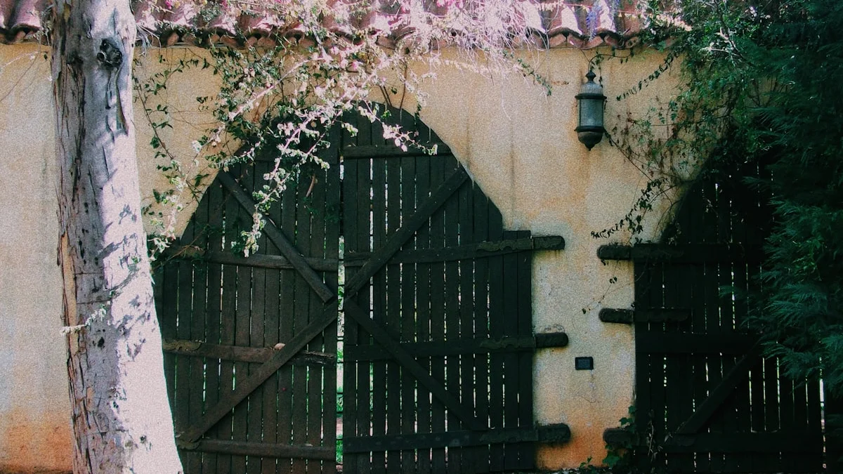 A rustic black wooden double gate set in a cream stucco wall waits beneath a small wrought-iron lantern. — a The Obsidian Key guide to Walking of the Unmarked Path: One Opening a Day.