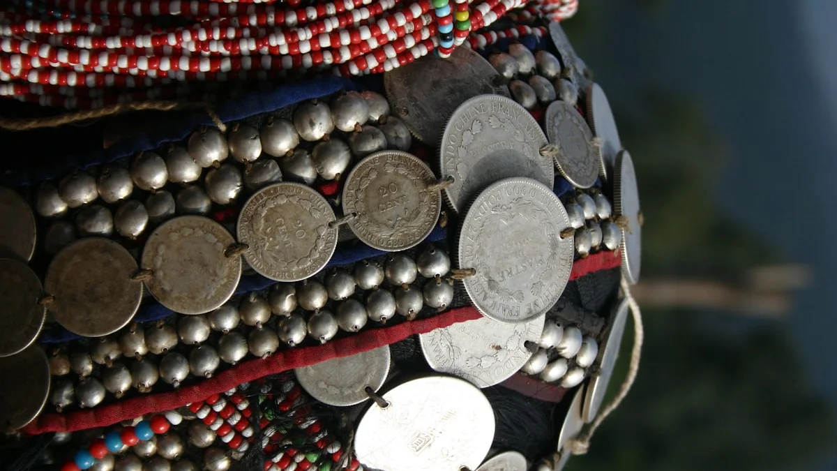 Rows of vintage silver coins stitched onto dark fabric beside colorful beads. — a The Obsidian Key guide to What Real Spiritual Teaching Should Cost.
